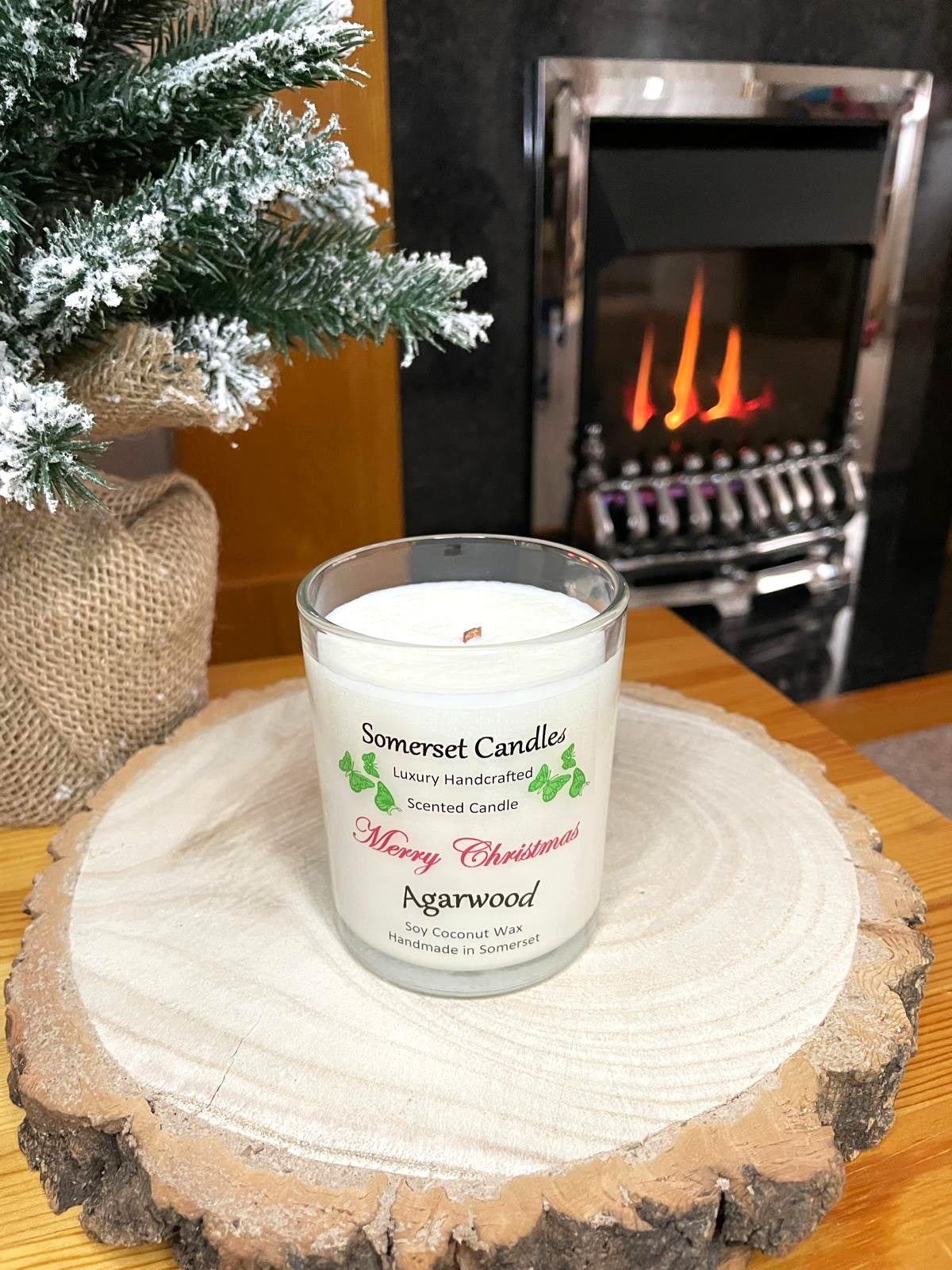 White soy candle in a 7oz clear glass jar with a natural wooden lid. The candle is made from a soy-coconut blend and scented with woodsie scent of agarwood. Above the scent name on the label, several orange butterflies are displayed, adding a romantic touch. Clean, minimalist design ideal for gifts, home decor or self-care.
