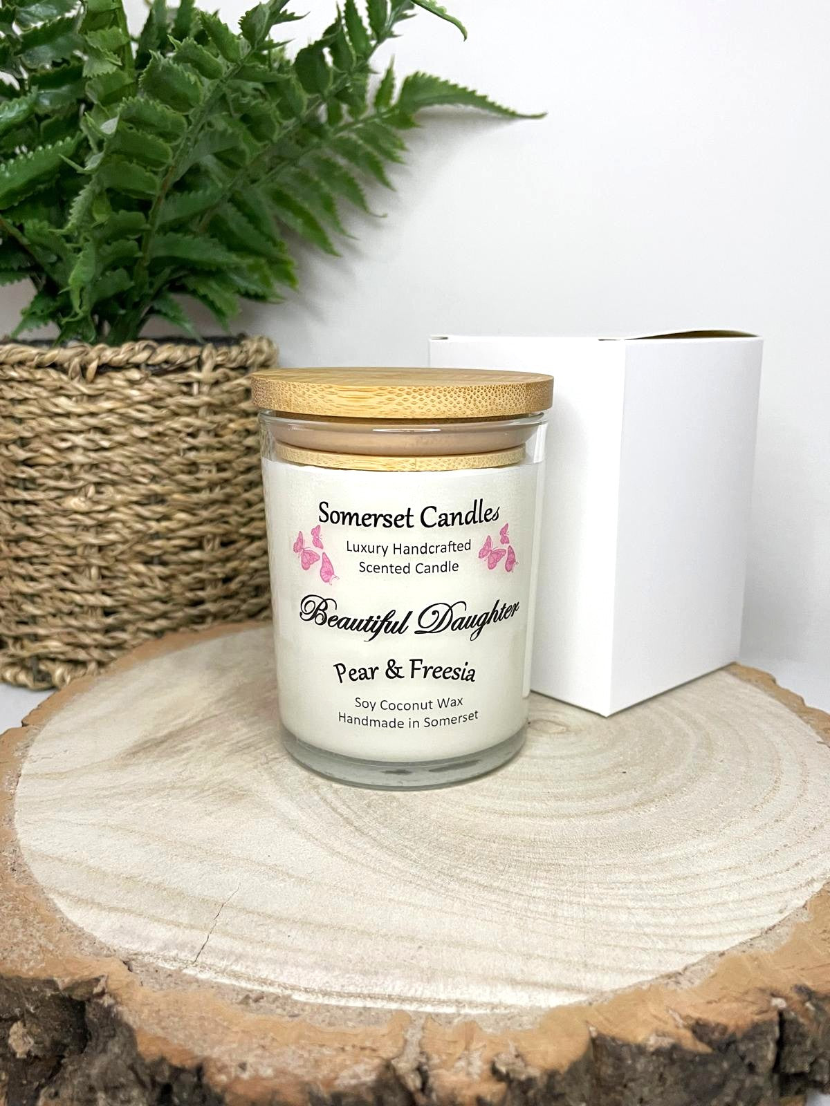 White soy candle in a 7oz clear glass jar with a natural wooden lid. The candle is made from a soy-coconut blend and scented with a delicate mix of pear and freesia. Above the scent name on the label, several pink butterflies are displayed, adding a romantic touch. Clean, minimalist design ideal for gifts, home decor or self-care.