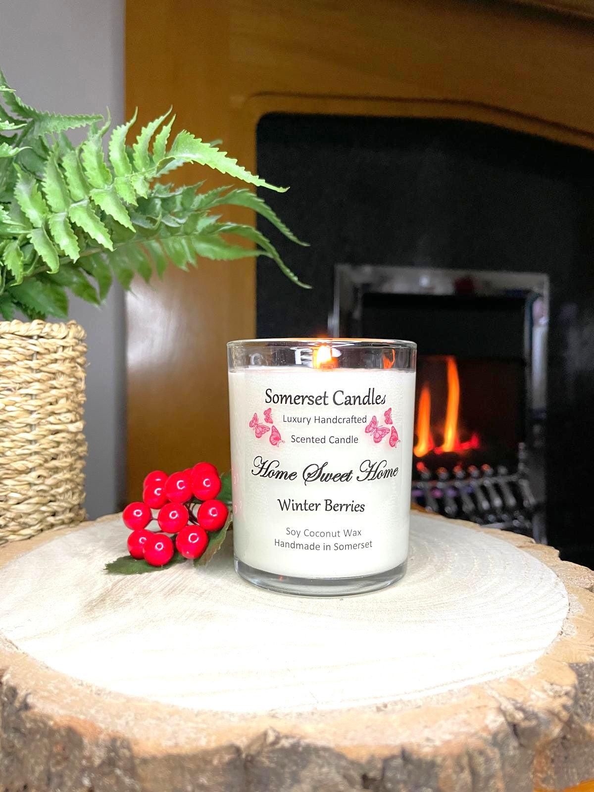 White soy candle in a 7oz clear glass jar with a natural wooden lid. The candle is made from a soy-coconut blend and scented with fruity winter berries. Above the scent name on the label, several red butterflies are displayed, adding a romantic touch. Clean, minimalist design ideal for gifts, home decor or self-care.
