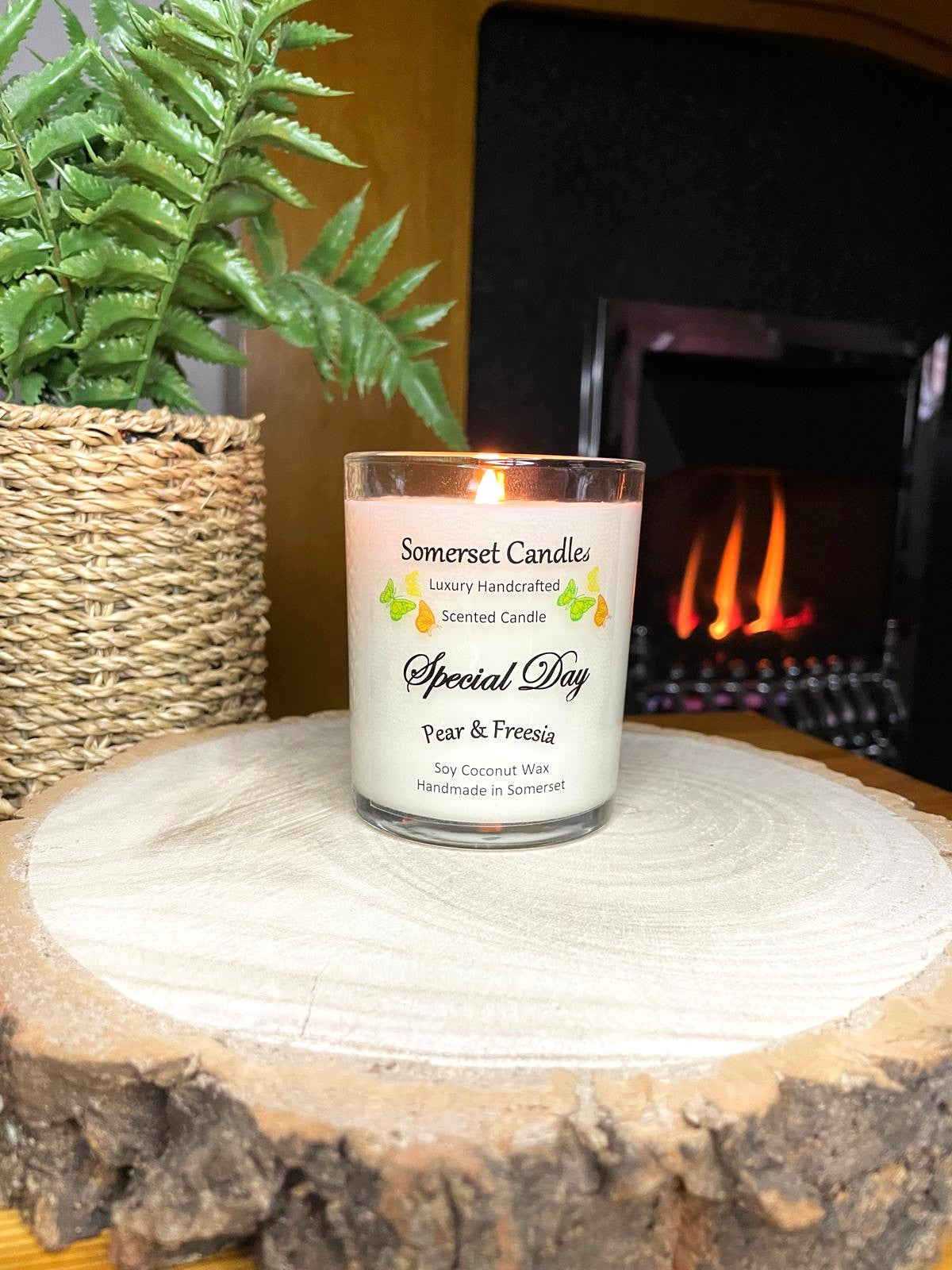 White soy candle in a 7oz clear glass jar with a natural wooden lid. The candle is made from a soy-coconut blend and scented with a delicate fruity floral scent of pear and freesia. Above the scent name on the label, several yellow, green and orange butterflies are displayed, adding a romantic touch. Clean, minimalist design ideal for gifts, home decor or self-care.