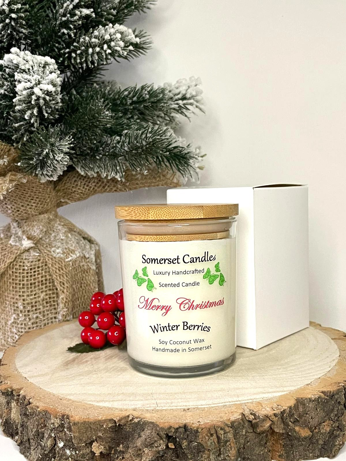 White soy candle in a 7oz clear glass jar with a natural wooden lid. The candle is made from a soy-coconut blend and scented with a fruity scent of winter berries. Above the scent name on the label, several red butterflies are displayed, adding a romantic touch. Clean, minimalist design ideal for gifts, home decor or self-care.