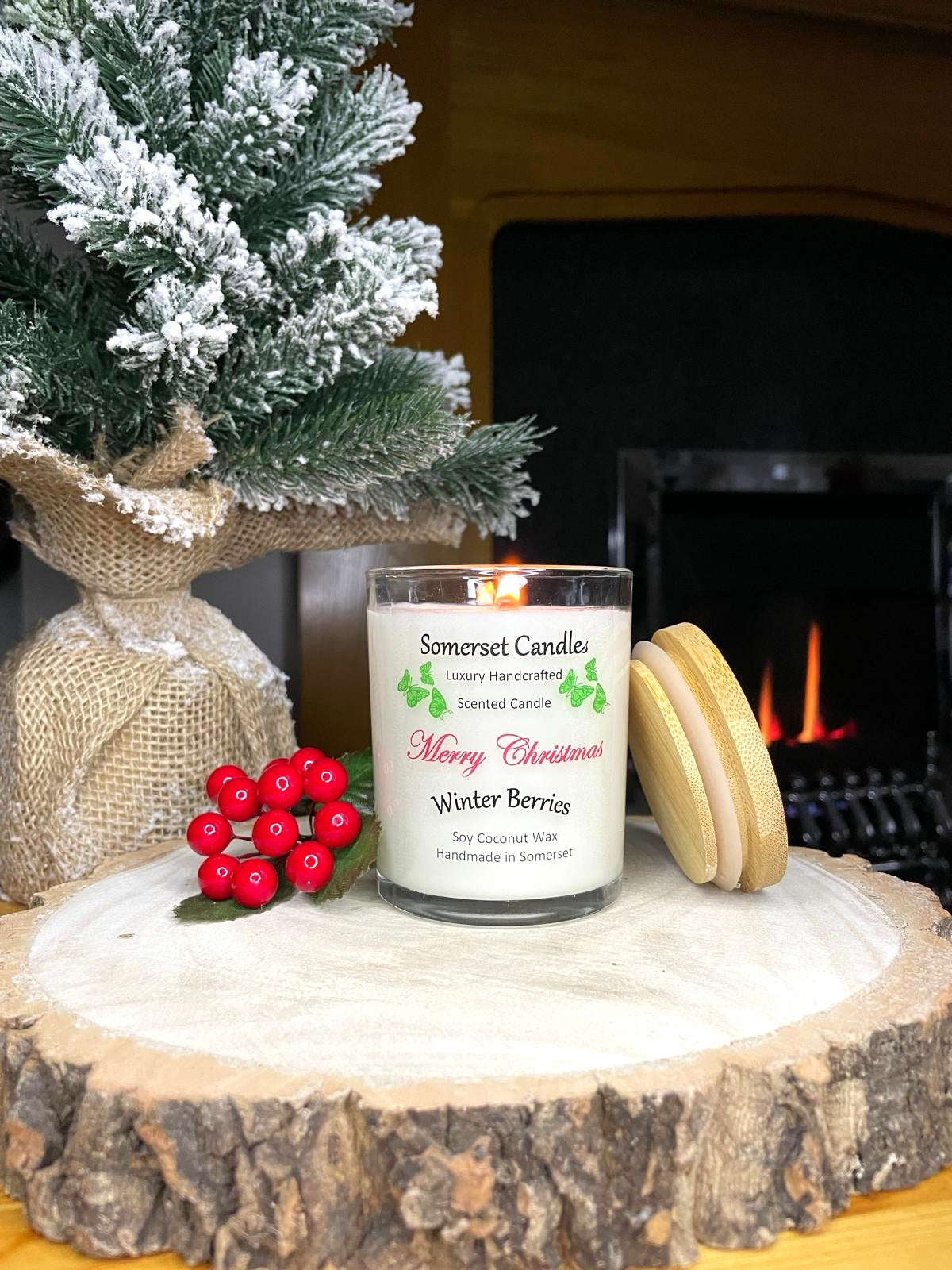 White soy candle in a 7oz clear glass jar with a natural wooden lid. The candle is made from a soy-coconut blend and scented with a fruity scent of winter berries. Above the scent name on the label, several red butterflies are displayed, adding a romantic touch. Clean, minimalist design ideal for gifts, home decor or self-care.