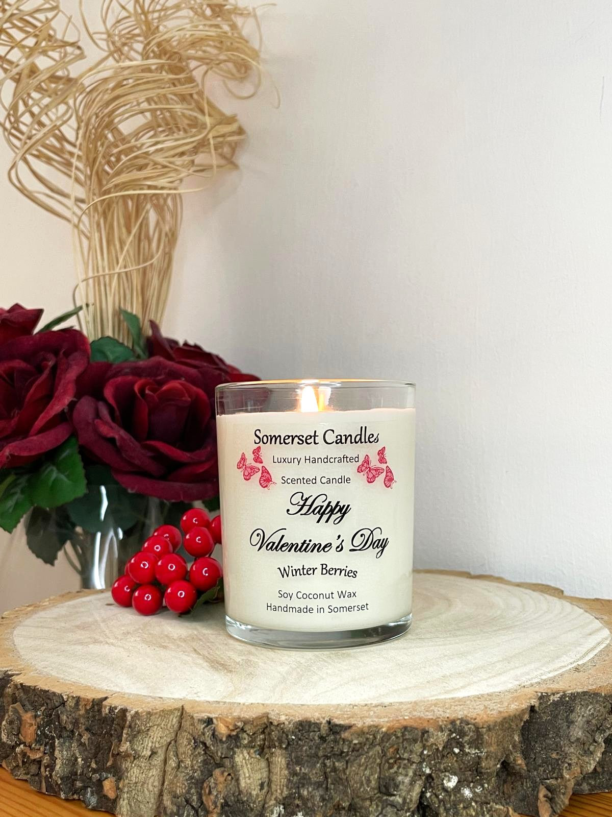 White soy candle in a 7oz clear glass jar with a natural wooden lid. The candle is made from a soy-coconut blend and scented with fruity winter berries. Above the scent name on the label, several red butterflies are displayed, adding a romantic touch. Clean, minimalist design ideal for gifts, home decor or self-care.