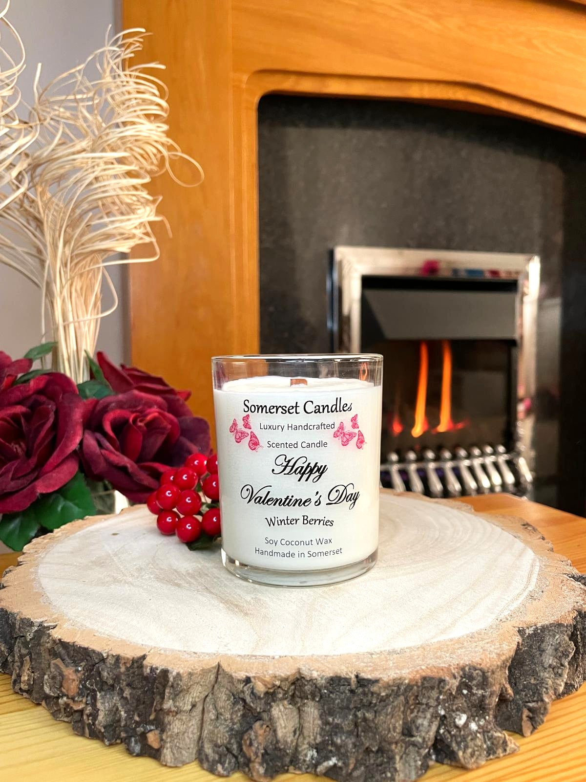 White soy candle in a 7oz clear glass jar with a natural wooden lid. The candle is made from a soy-coconut blend and scented with fruity winter berries. Above the scent name on the label, several red butterflies are displayed, adding a romantic touch. Clean, minimalist design ideal for gifts, home decor or self-care.