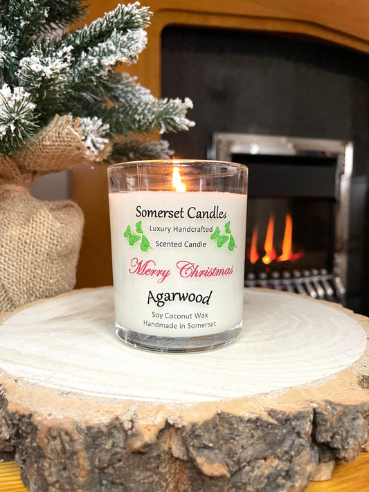 White soy candle in a 7oz clear glass jar with a natural wooden lid. The candle is made from a soy-coconut blend and scented with woodsie scent of agarwood. Above the scent name on the label, several orange butterflies are displayed, adding a romantic touch. Clean, minimalist design ideal for gifts, home decor or self-care.