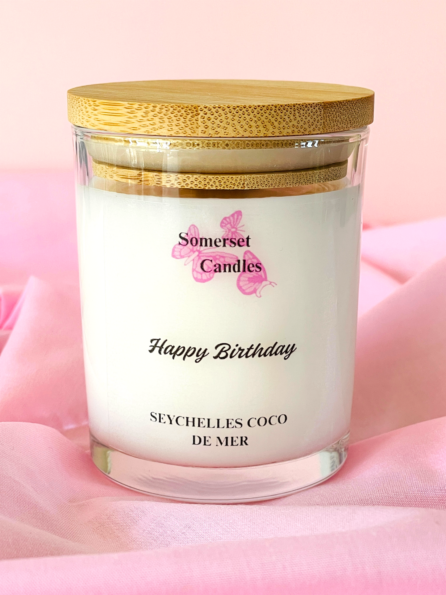 Somerset Candles 'Happy Birthday Seychelles Coco de Mer' candle on a pink background