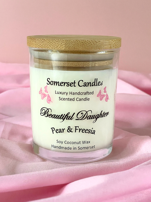 Somerset Candles scented candle with a wooden lid on a pink fabric background