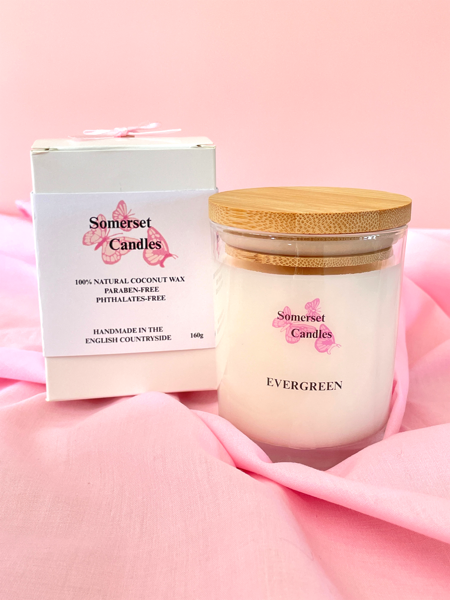 Somerset Candles jar with wooden lid and packaging on a pink fabric background