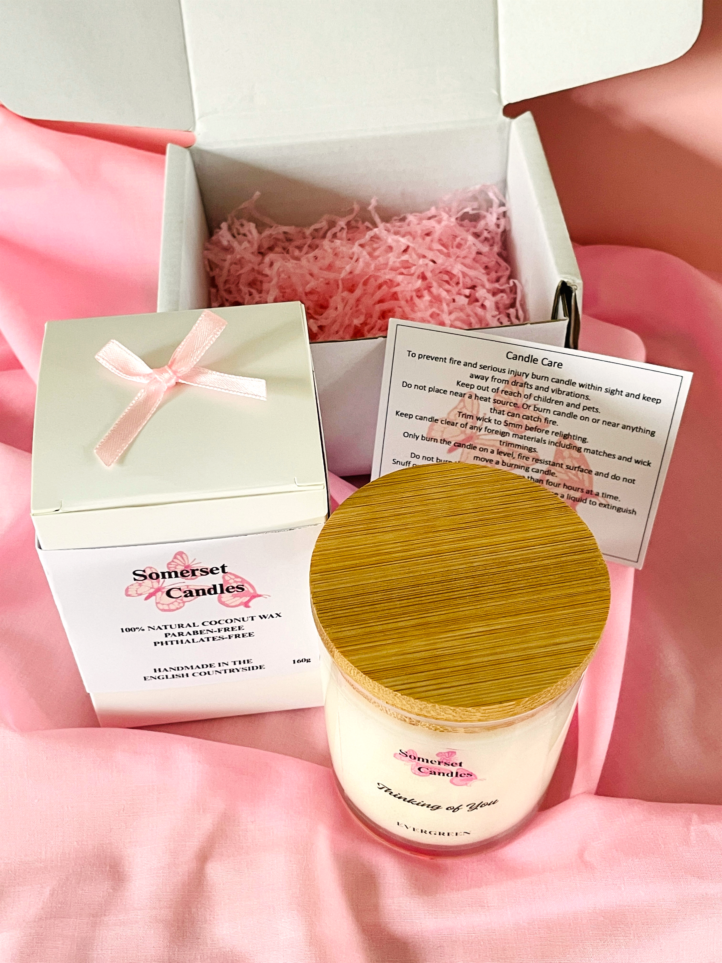 Somerset Candles jar with wooden lid and packaging on a pink fabric background
