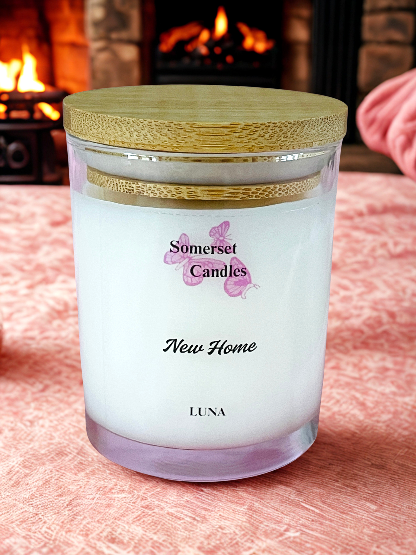 Somerset Candles New Home Luna candle on a soft surface with a fireplace in the background