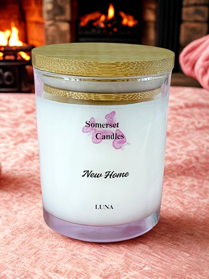 Somerset Candles New Home Luna candle on a soft surface with a fireplace in the background