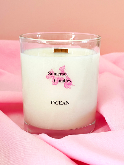 Candle labeled 'Somerset Candles Ocean' on a pink fabric background