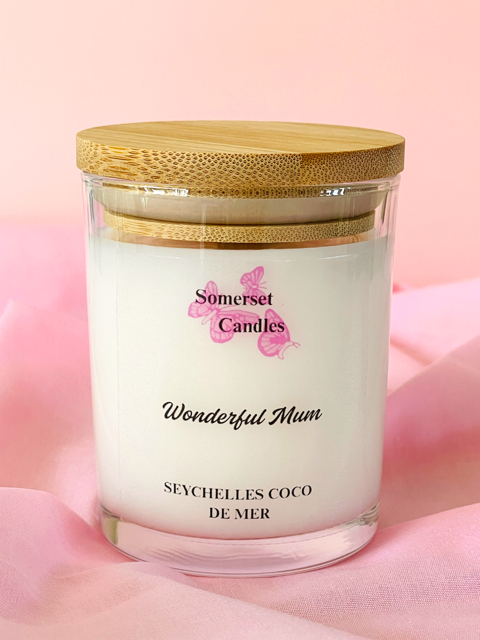 Somerset Candles 'Wonderful Mum' Seychelles Coco de Mer candle with a wooden lid on a pink background