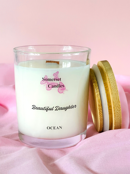Somerset Candles 'Beautiful Daughter' candle with wooden lid on pink fabric background
