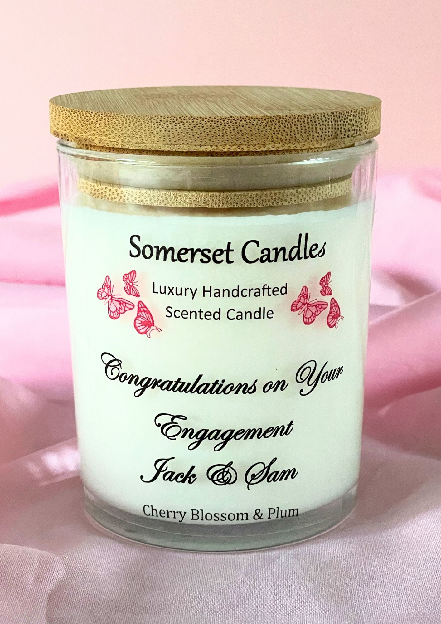 Somerset Candles engagement-themed candle with wooden lid on a pink fabric background