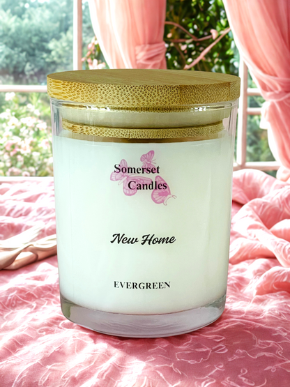 Somerset Candles New Home Evergreen candle on a pink surface with blurred outdoor background