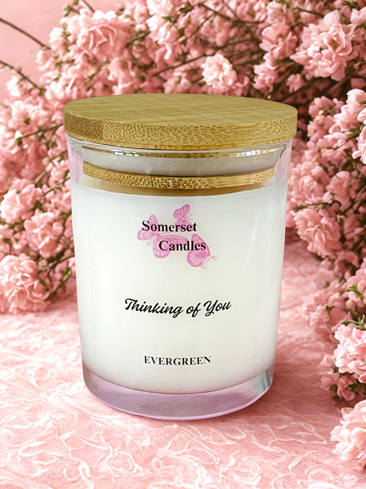Somerset Candles 'Thinking of You' candle with a wooden lid against a pink floral background