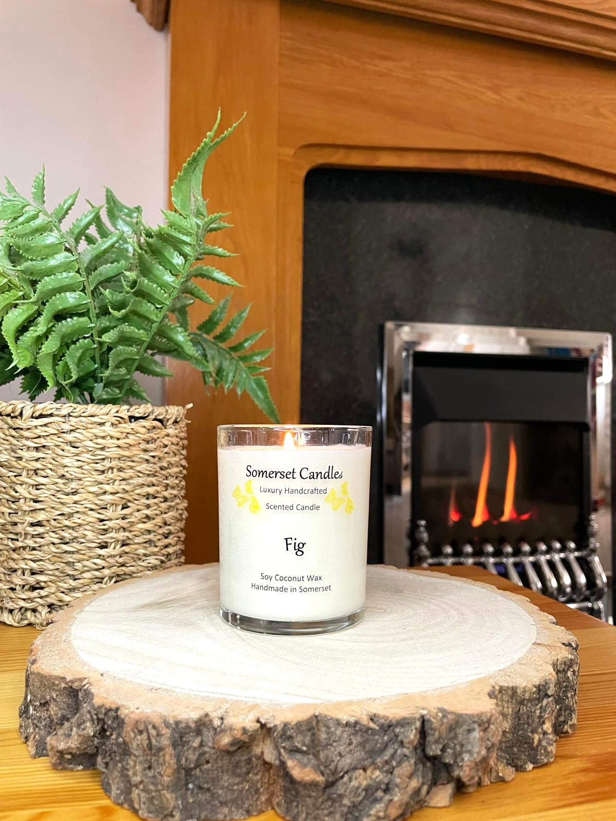White soy candle in a 7oz clear glass jar with a natural wooden lid. The candle is made from a soy-coconut blend and scented with a fresh scent of ripe fig. Above the scent name on the label, several yellow butterflies are displayed, adding a romantic touch. Clean, minimalist design ideal for gifts, home decor or self-care.
