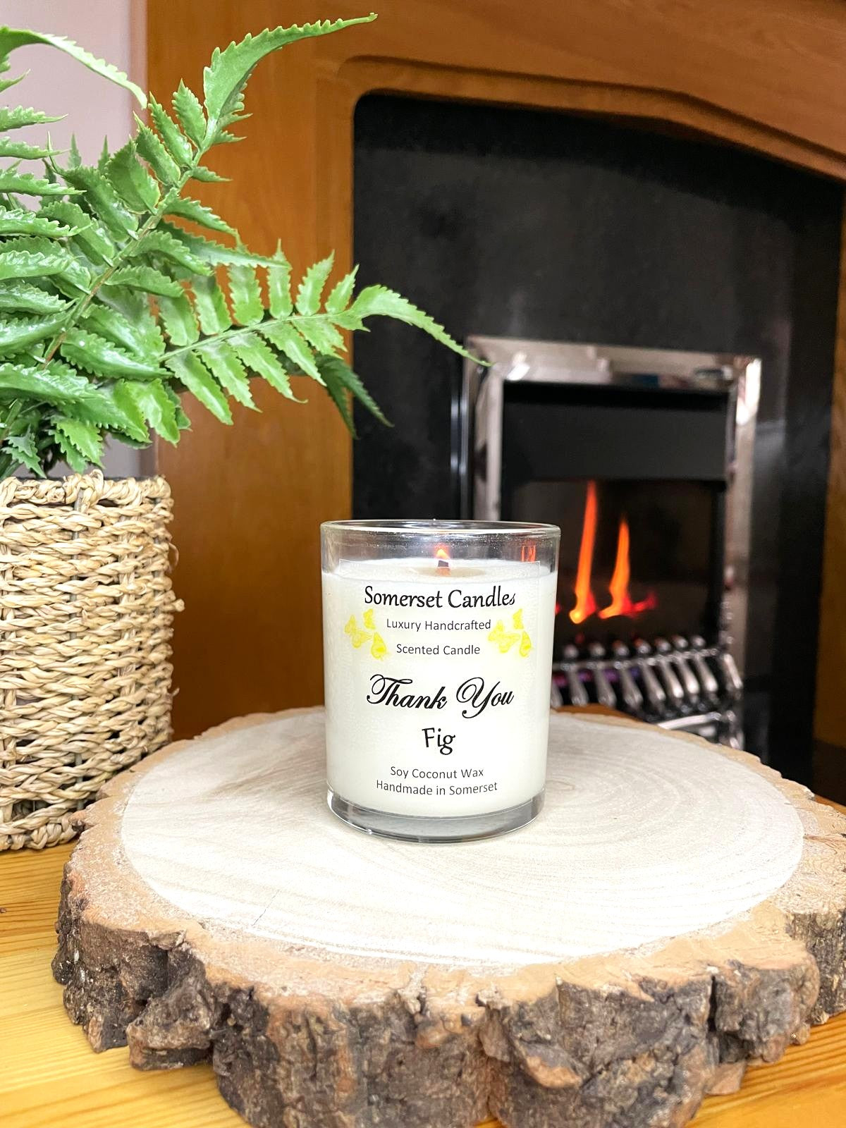 White soy candle in a 7oz clear glass jar with a natural wooden lid. The candle is made from a soy-coconut blend and scented with ripe fig. Above the scent name on the label, several yellow butterflies are displayed, adding a romantic touch. Clean, minimalist design ideal for gifts, home decor or self-care.