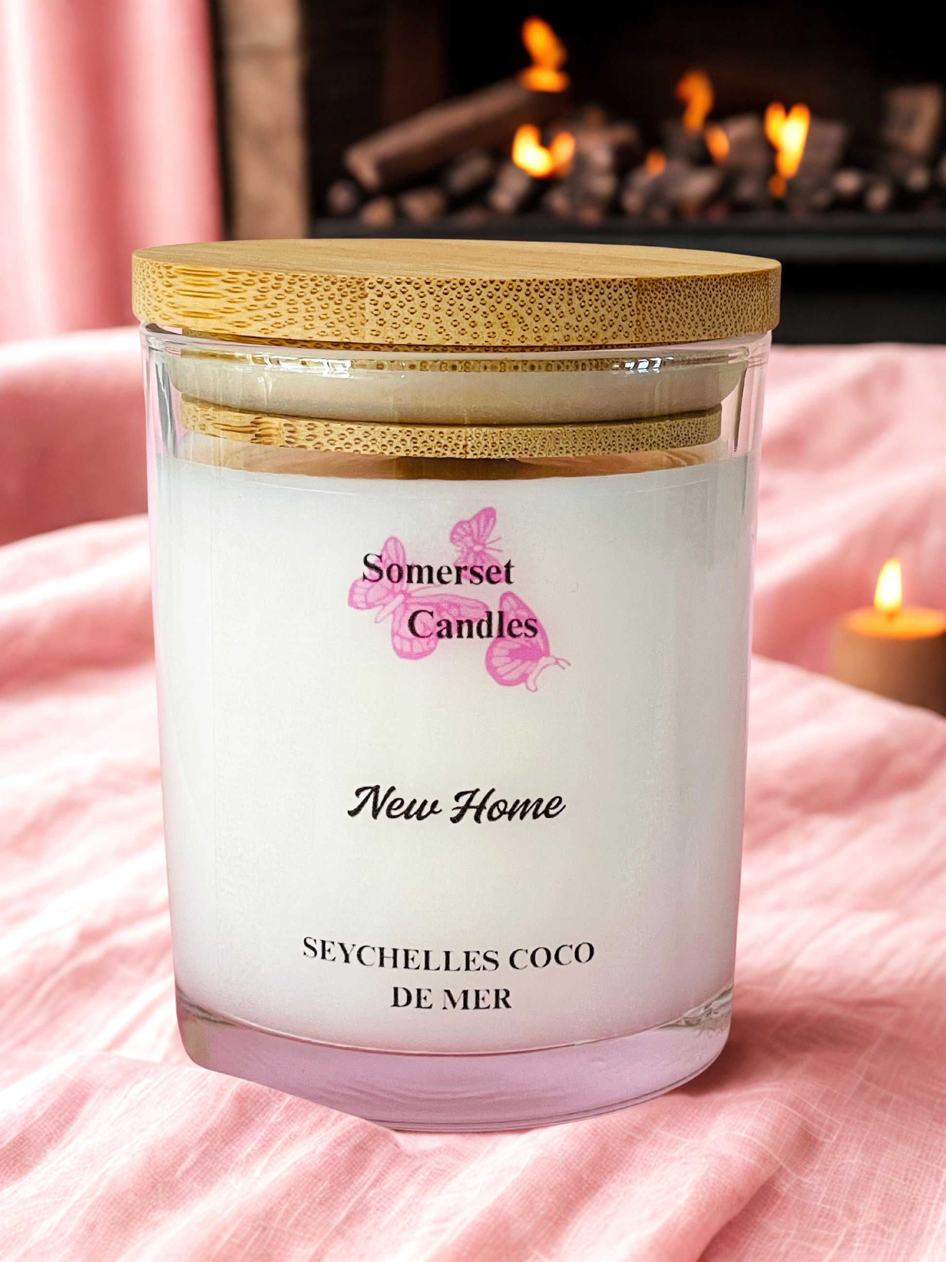 Somerset Candles New Home Seychelles Coco de Mer candle with a wooden lid on a pink blanket.