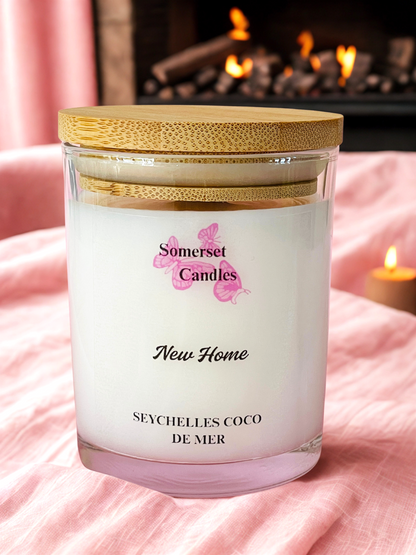 Somerset Candles New Home Seychelles Coco de Mer candle with a wooden lid on a pink blanket.