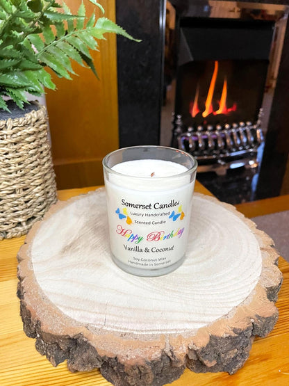 White soy candle in a 7oz clear glass jar with a natural wooden lid. The candle is made from a soy-coconut blend and scented with vanilla and coconut. Above the scent name on the label, several yellow, orange and blue butterflies are displayed, adding a romantic touch. Clean, minimalist design ideal for gifts, home decor or self-care.