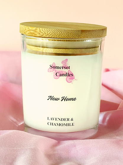 Scented candle in a glass jar with a gold lid on a pink fabric background, featuring 'Somerset Candles' branding.