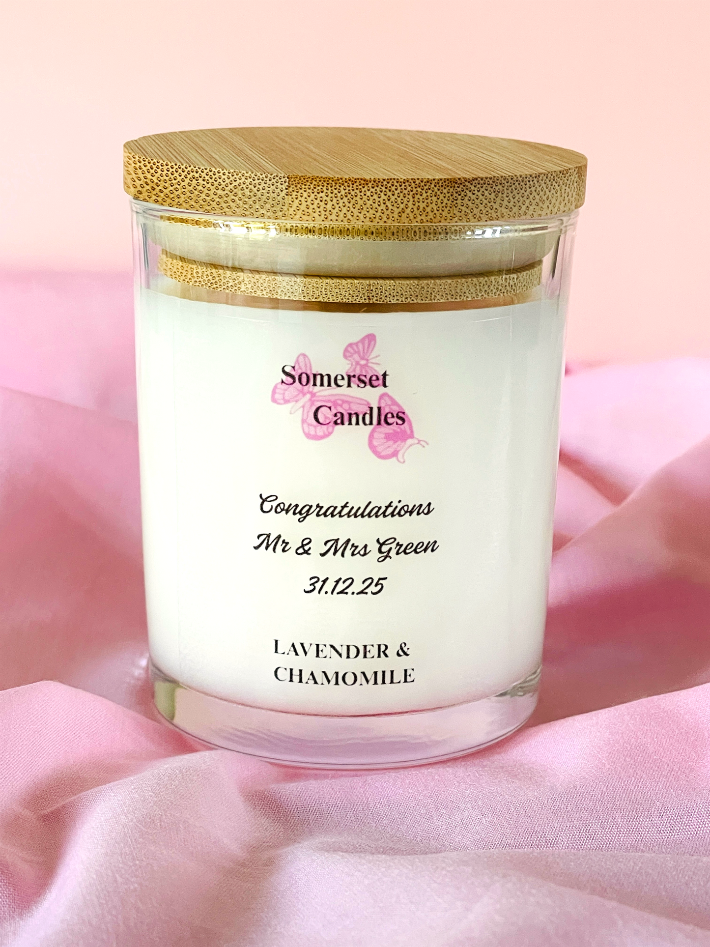 Personalized candle with wooden lid on a pink background