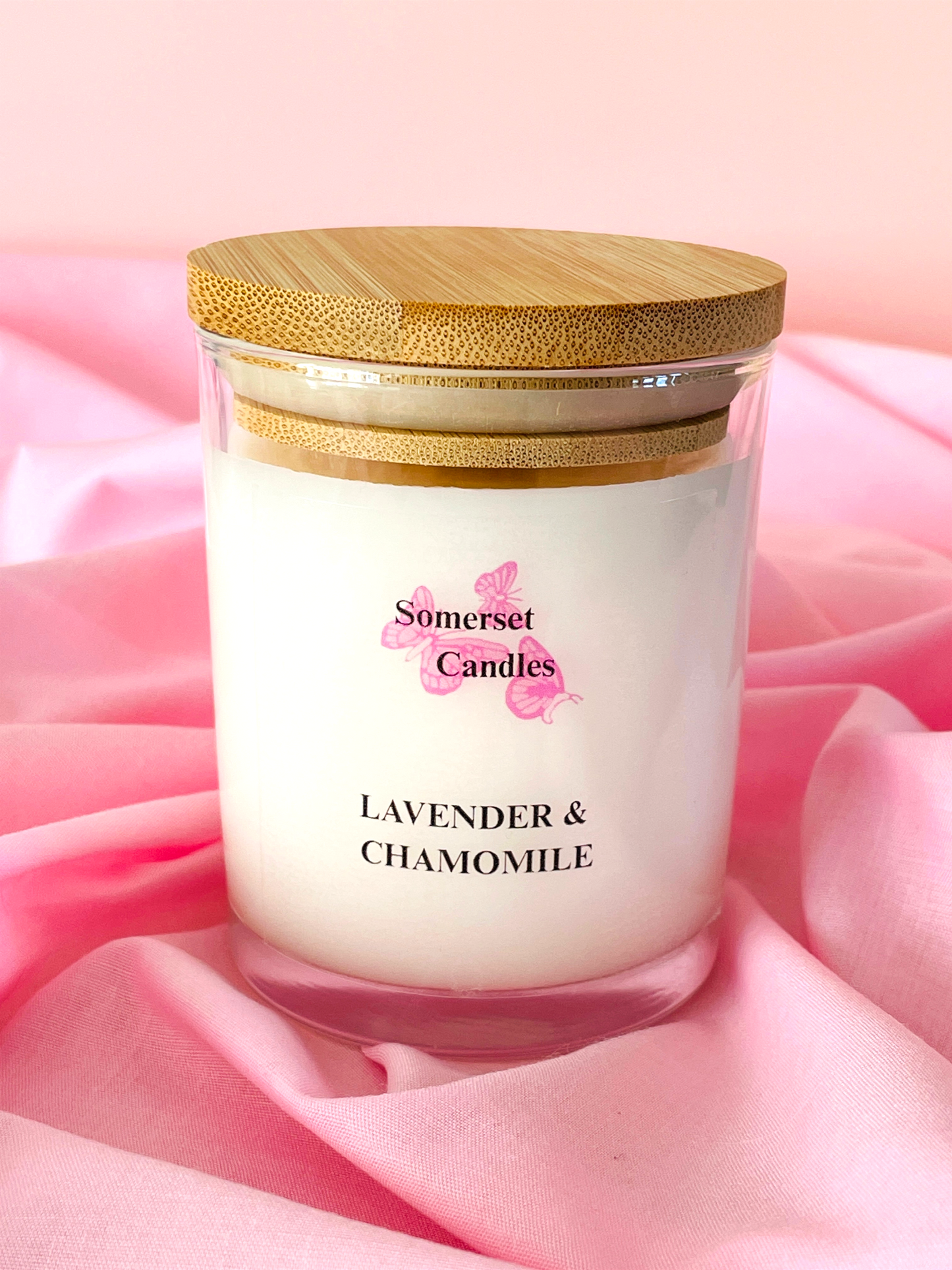 Somerset Candles lavender and chamomile candle with a wooden lid on pink fabric