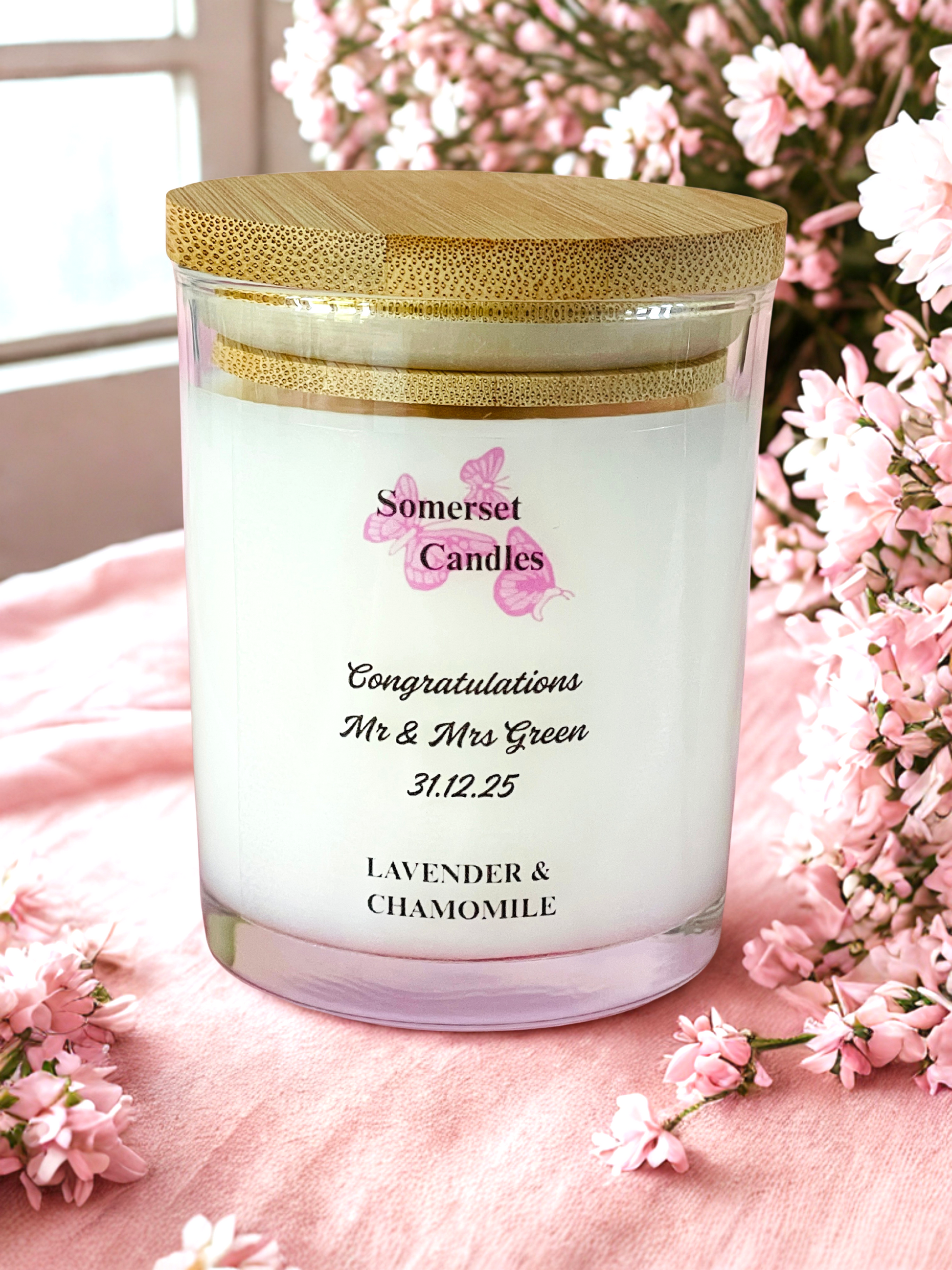 Personalized candle with a wooden lid on a pink surface with flowers