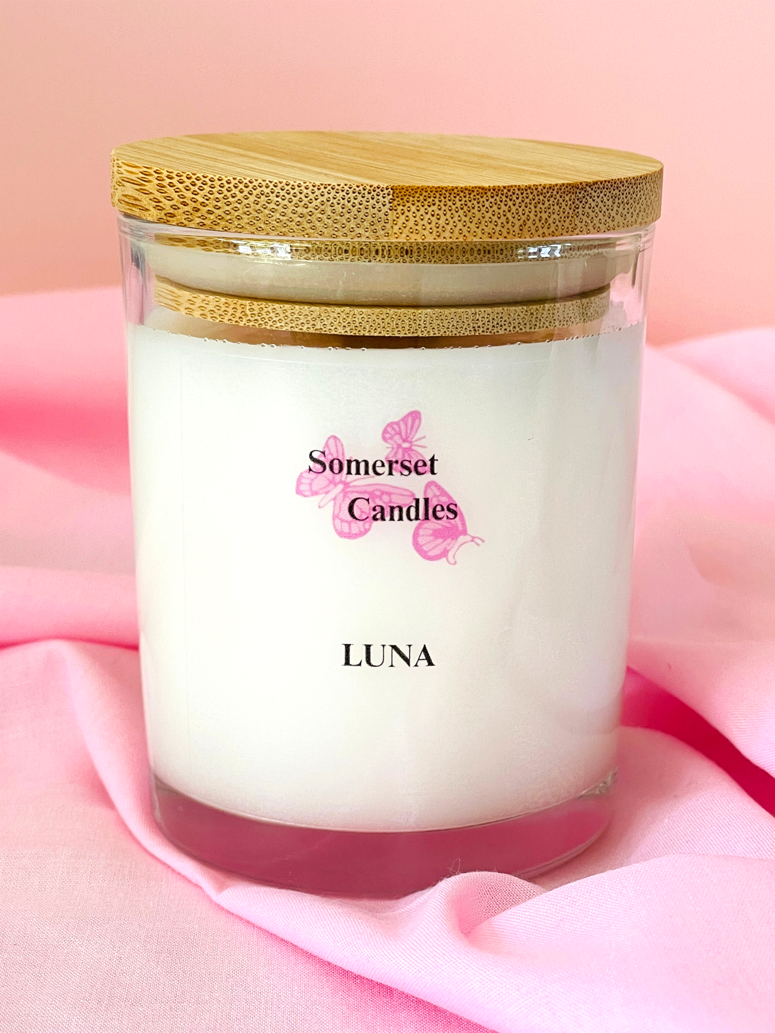 Somerset Candles Luna candle with a gold lid on a pink fabric background