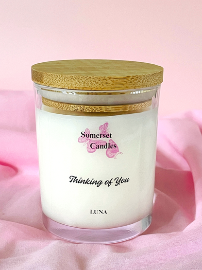 Candle in a glass jar with a wooden lid on a pink background, featuring 'Somerset Candles' branding.