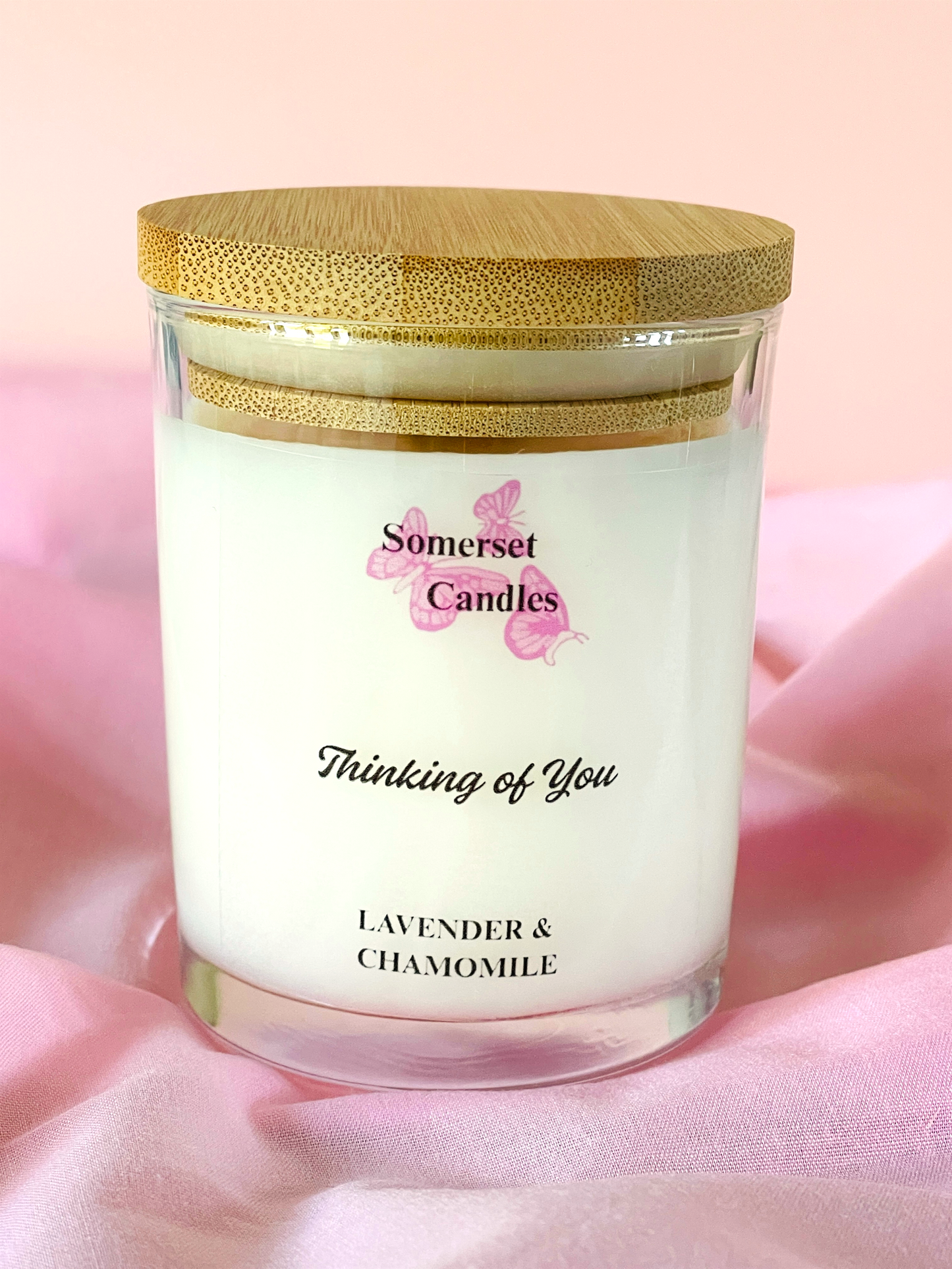 Somerset Candles 'Thinking of You' lavender and chamomile candle with a wooden lid on a soft pink background.
