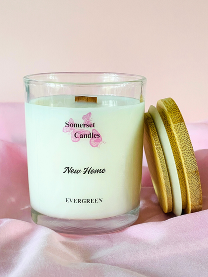 Somerset Candles New Home Evergreen candle with a wooden lid on a pink background