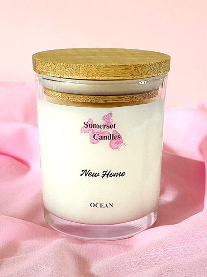 Somerset Candles New Home Ocean candle with wooden lid on a pink fabric background