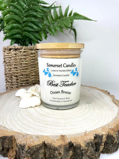 White soy candle in a 7oz clear glass jar with a natural wooden lid. The candle is made from a soy-coconut blend and scented with a fresh scent of ocean breeze. Above the scent name on the label, several blue butterflies are displayed, adding a romantic touch. Clean, minimalist design ideal for gifts, home decor or self-care.