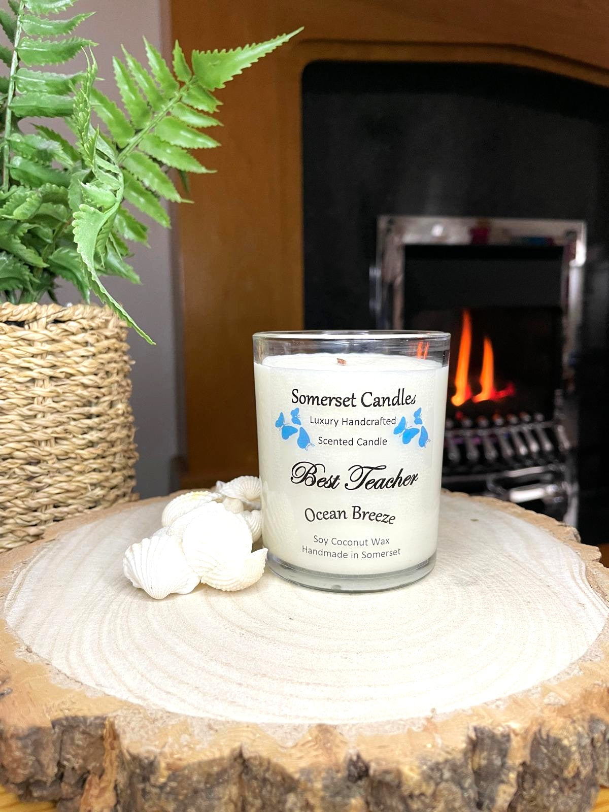 White soy candle in a 7oz clear glass jar with a natural wooden lid. The candle is made from a soy-coconut blend and scented with a fresh scent of ocean breeze. Above the scent name on the label, several blue butterflies are displayed, adding a romantic touch. Clean, minimalist design ideal for gifts, home decor or self-care.