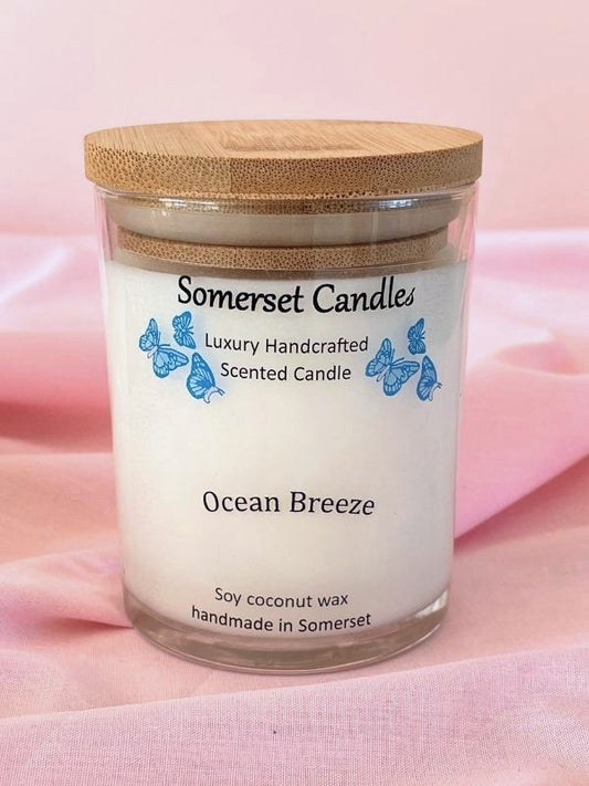 Somerset Candles Ocean Breeze candle with a wooden lid on a pink fabric background