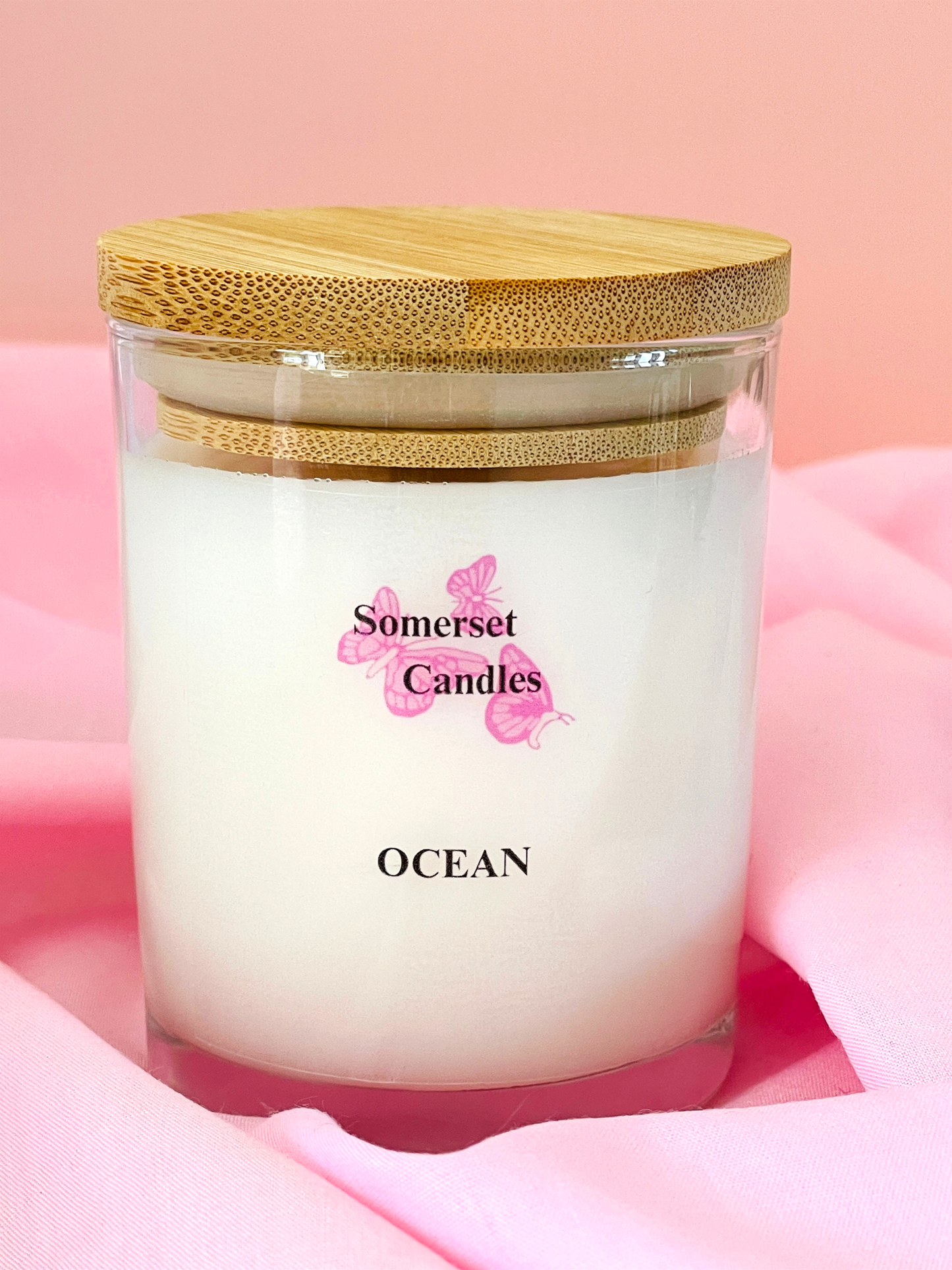 Somerset Candles Ocean scented candle with a wooden lid on a pink background