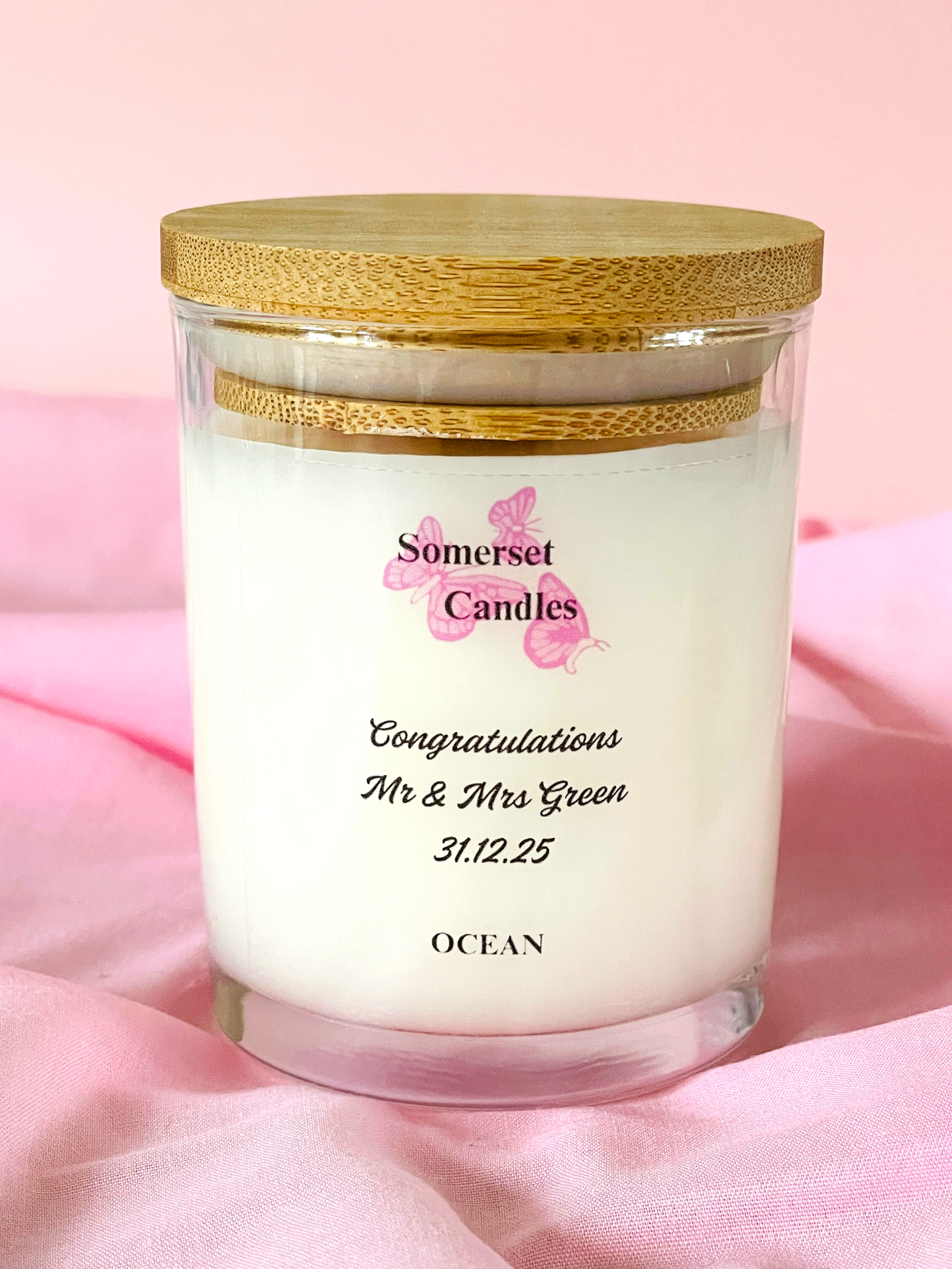 Somerset Candles 'Congratulations Mr & Mrs' ocean-scented candle on a pink fabric background