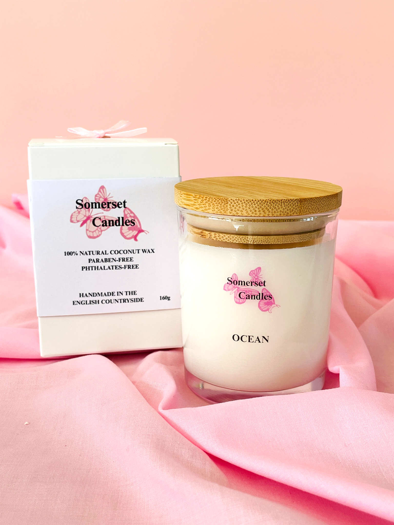 Somerset Candles jar with gold lid on pink fabric background