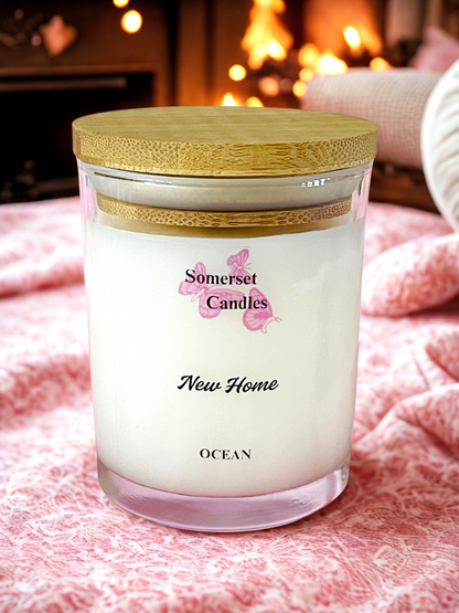 Somerset Candles 'New Home Ocean' candle with a wooden lid on a soft surface.