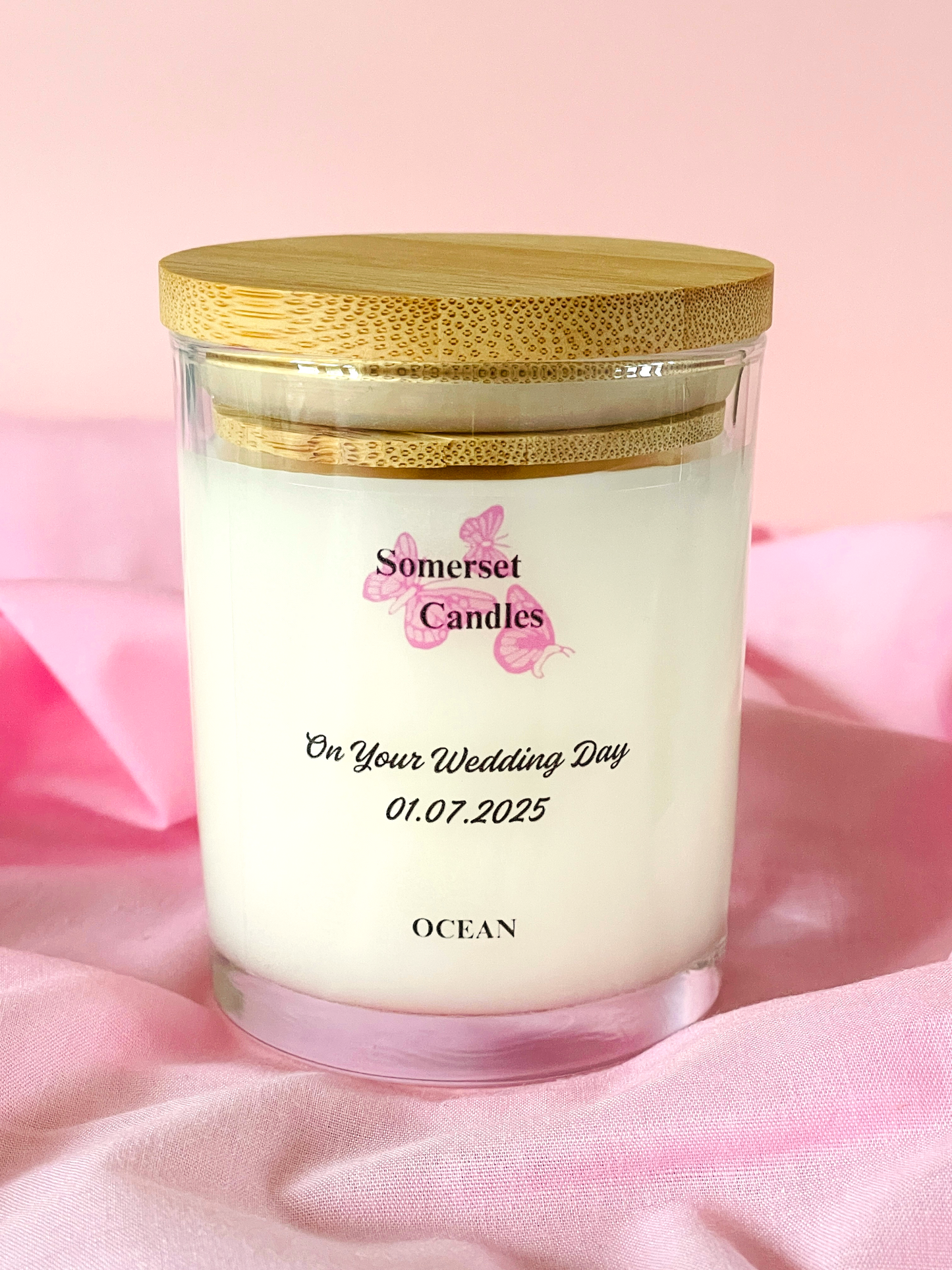 Personalised candle with 'Somerset Candles' branding on a pink fabric background