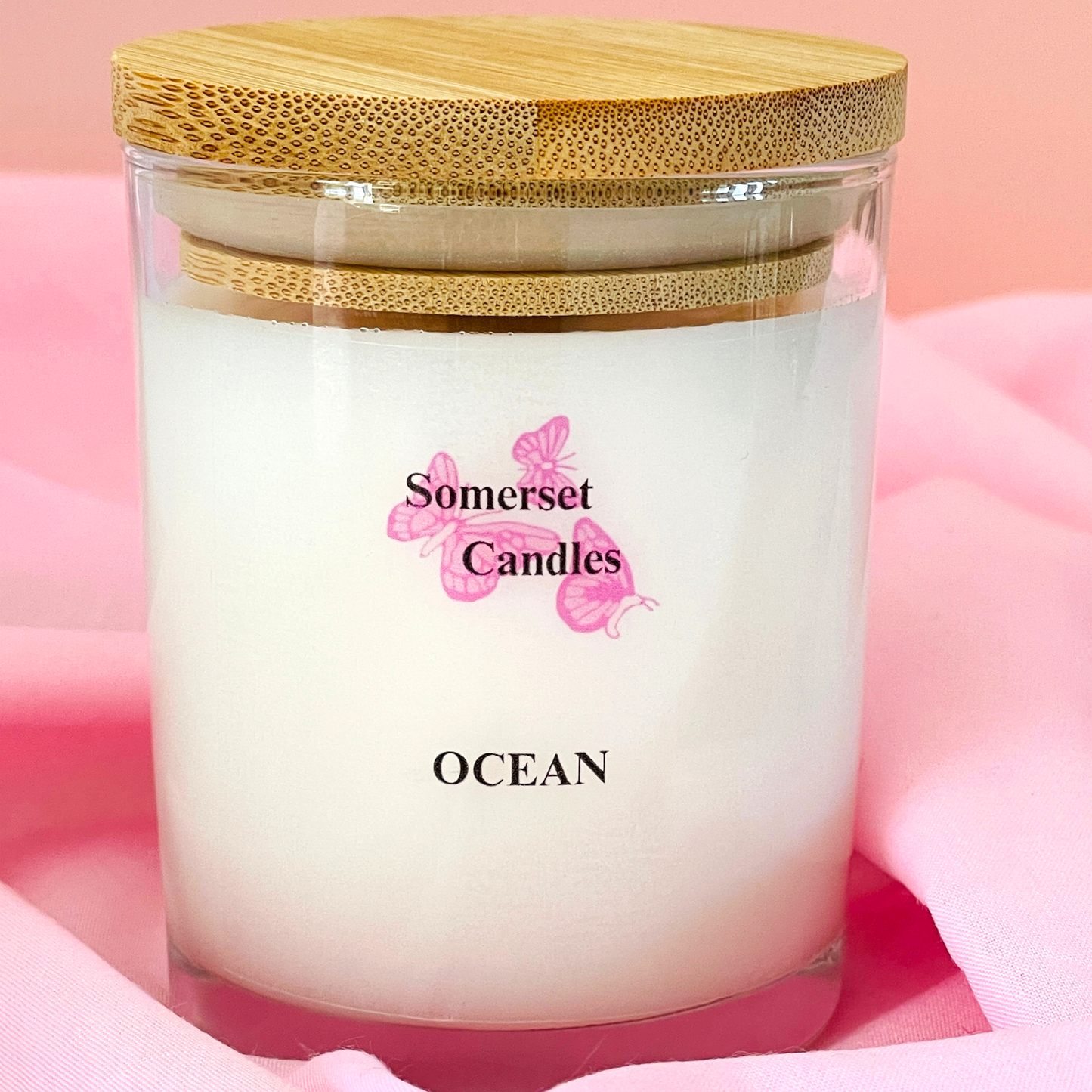 Somerset Candles Ocean scented candle with a wooden lid on a pink background