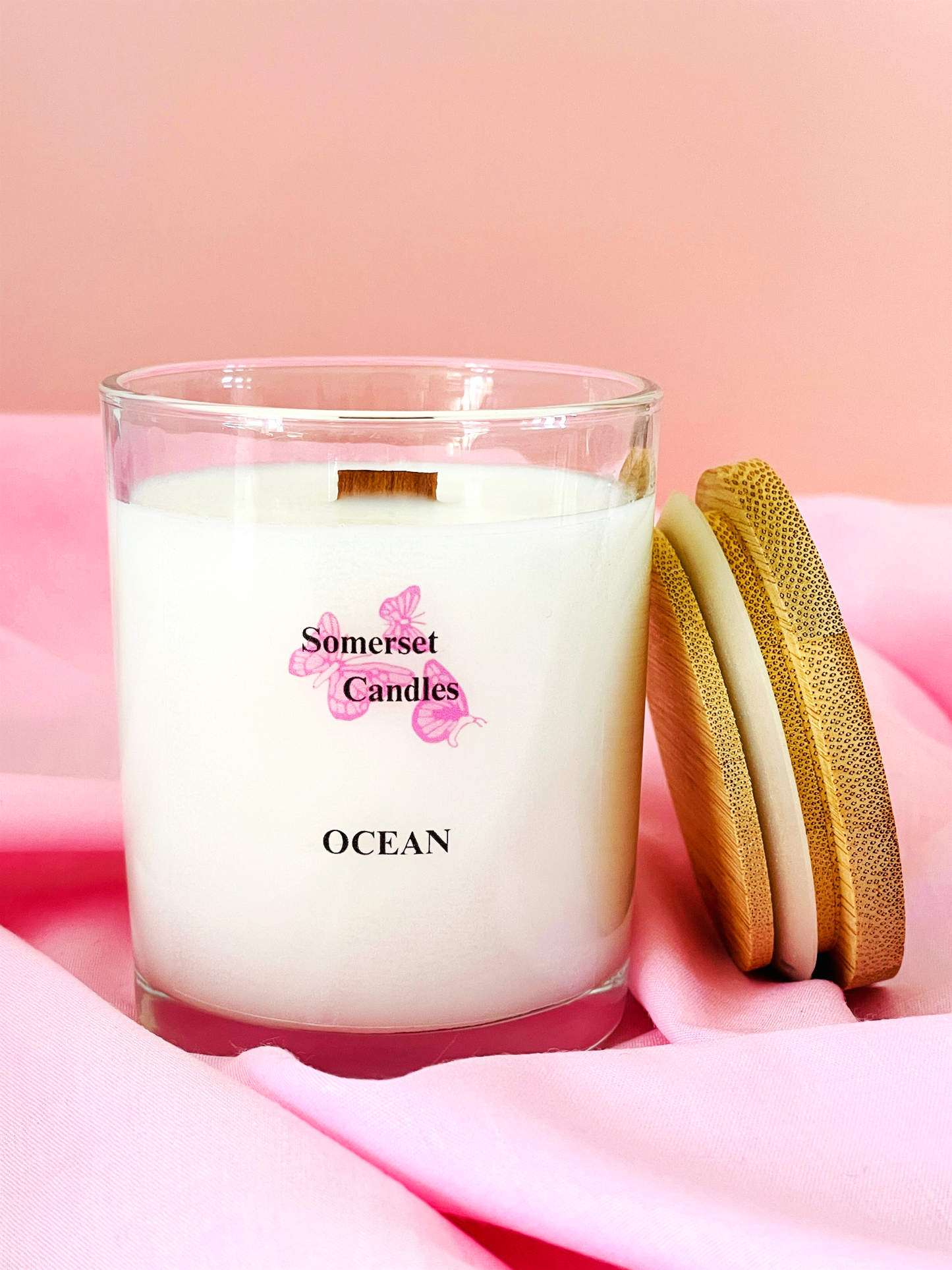 Somerset Candles Ocean candle with wooden lid on pink fabric