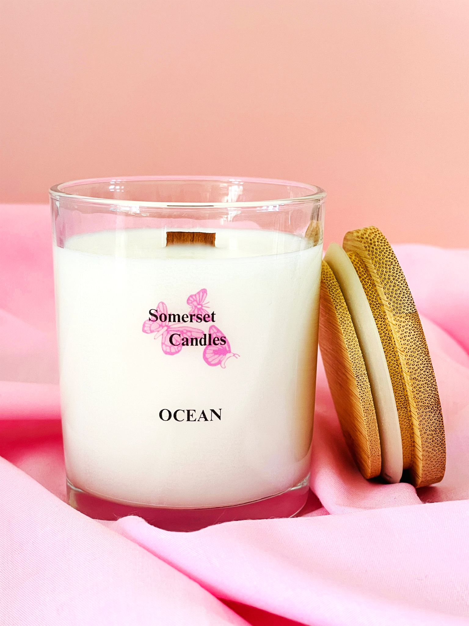 Somerset Candles Ocean candle with wooden lid on pink fabric