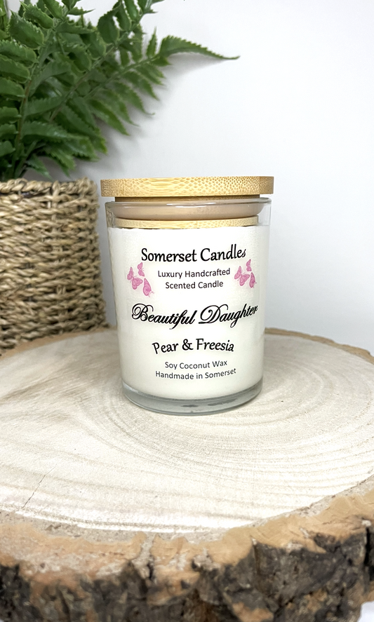 White soy candle in a 7oz clear glass jar with a natural wooden lid. The candle is made from a soy-coconut blend and scented with a delicate mix of pear and freesia. Above the scent name on the label, several pink butterflies are displayed, adding a romantic touch. Clean, minimalist design ideal for gifts, home decor or self-care.