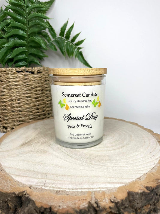 White soy candle in a 7oz clear glass jar with a natural wooden lid. The candle is made from a soy-coconut blend and scented with a delicate fruity floral scent of pear and freesia. Above the scent name on the label, several yellow, green and orange butterflies are displayed, adding a romantic touch. Clean, minimalist design ideal for gifts, home decor or self-care.