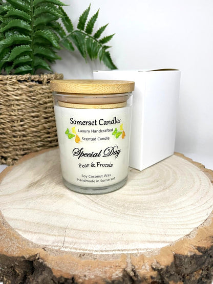 White soy candle in a 7oz clear glass jar with a natural wooden lid. The candle is made from a soy-coconut blend and scented with a delicate fruity floral scent of pear and freesia. Above the scent name on the label, several yellow, green and orange butterflies are displayed, adding a romantic touch. Clean, minimalist design ideal for gifts, home decor or self-care.