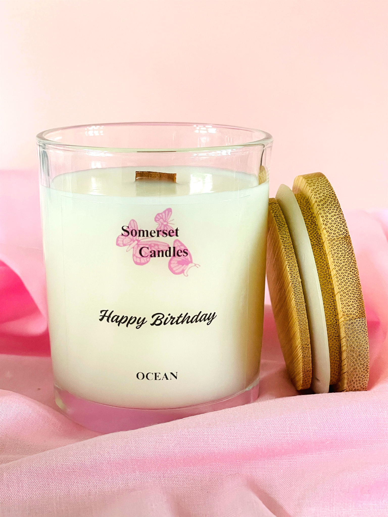 Somerset Candles 'Happy Birthday Ocean' candle on a pink fabric background